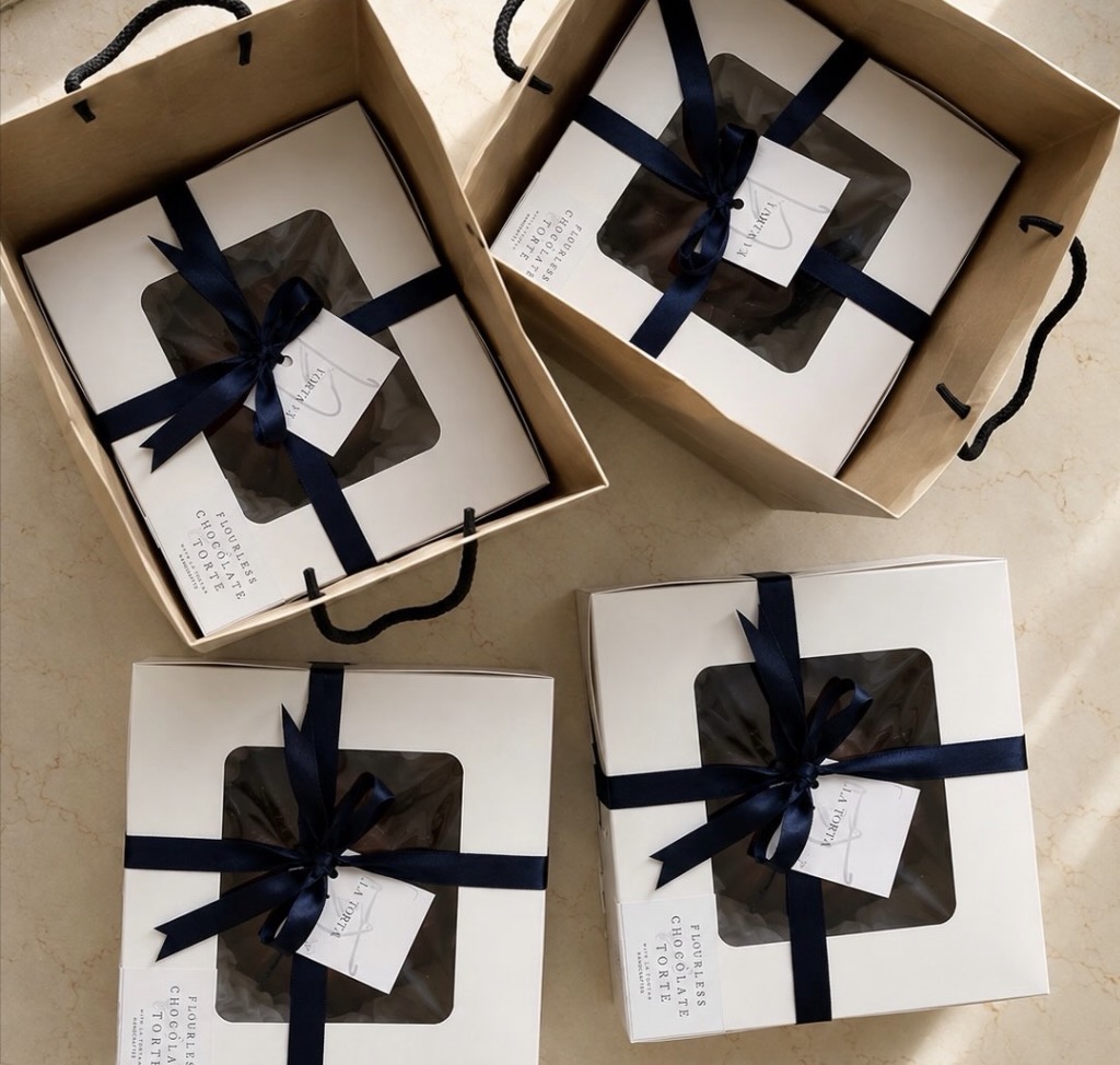 Flourless chocolate torté boxes tied with navy ribbon in gift bags