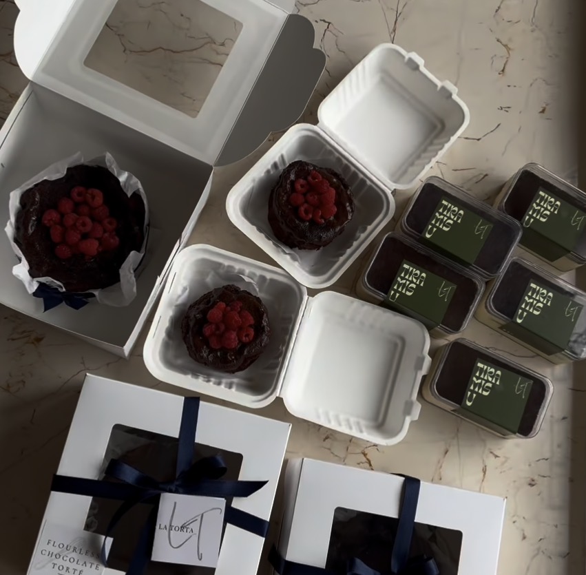 Raspberry-topped flourless tortés and tiramisu tubs boxed for delivery