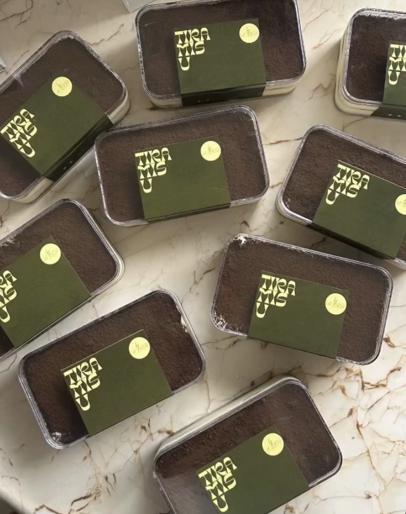 Tiramisu tubs with olive green La Torta sleeves arranged on marble